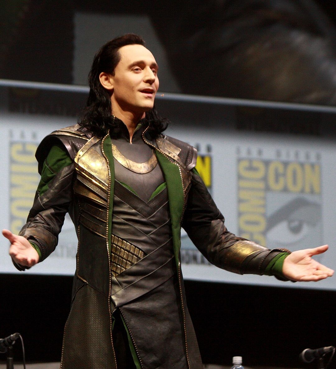 Tom Hiddleston souriant, micro à la main, lors d'une convention.